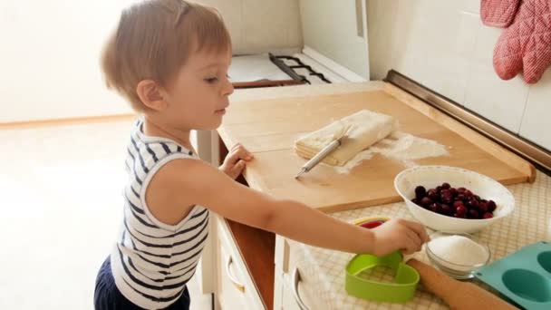 4k кадри чарівного маленького хлопчика з тістом та інгредієнтами для пирога на кухні — стокове відео