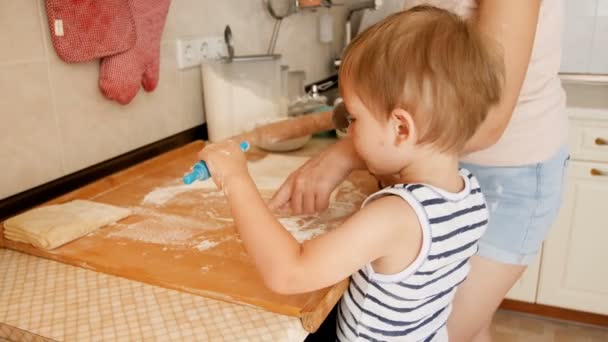 特写4k 视频小蹒跚学步的男孩与玩具滚动别针帮助他的母亲在厨房做馅饼 — 图库视频影像