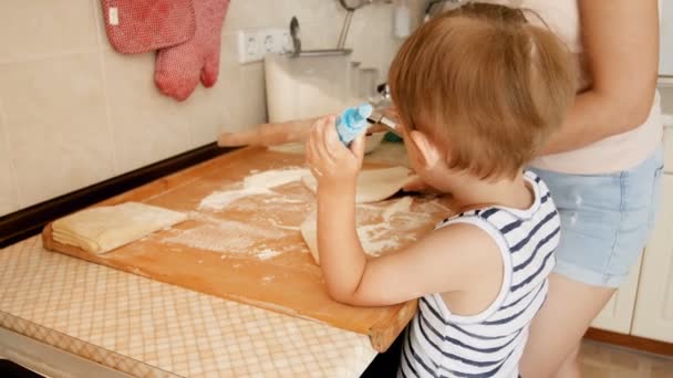 Närbild 4k-video av liten toddler pojke hjälper sin mamma att göra paj på kök — Stockvideo