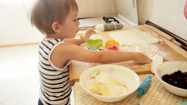 Filmagem 4k de 3 anos de idade menino colocando cereja na massa e polvilhe-lo com farinha. Conceito de pequeno chef — Vídeo de Stock