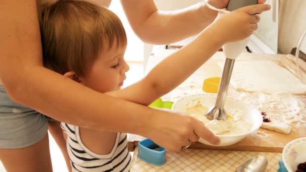 4 k wideo młode matki z 3 lat toddler chłopiec mieszając ciasto z blendera wykonawczy w misce — Wideo stockowe