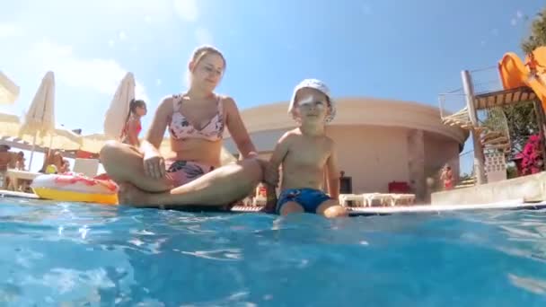 4k video de alegre sonriente niño sentado con la madre en la piscina en el hotel resort — Vídeo de stock