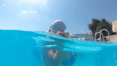 Yavaş hareket sualtı video tutarak ve küçük yürümeye başlayan çocuk oğlu yüzme havuzunda dönen Genç Anne
