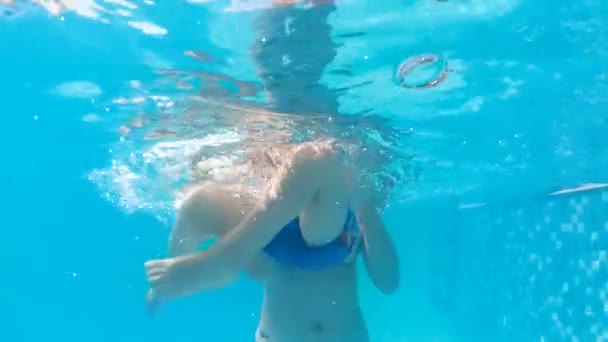 Vídeo subaquático em câmera lenta de um garoto alegre brincando com a mãe na piscina no aquapark — Vídeo de Stock