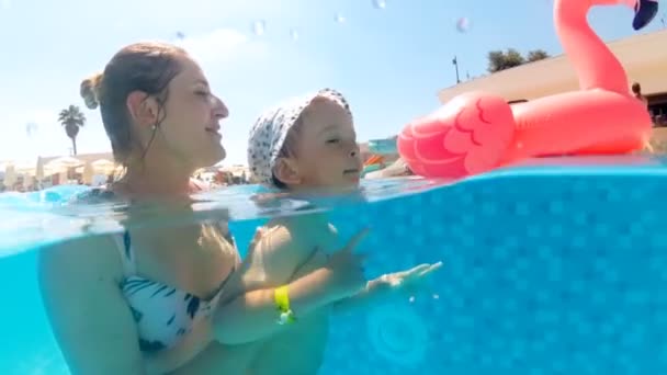 Slow motion onderwater video van vrolijk lachende moeder met zoon zwemmen in zwembad op warme zonnige dag — Stockvideo