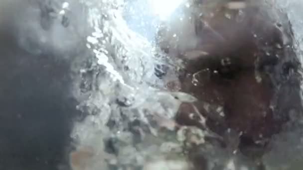 Vidéo au ralenti d'un jeune homme tenant une caméra d'action sautant et plongeant dans la mer depuis un ponton 