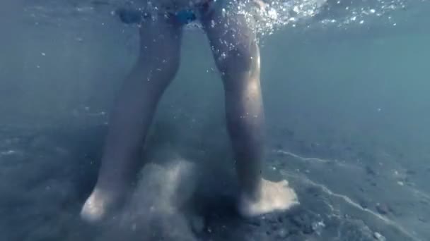 Filmagem subaquática em câmera lenta de pés de criança andando na praia de areia sob o mar — Vídeo de Stock