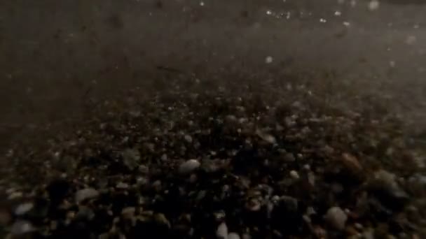 Gros plan au ralenti d'une vague de sable et de mauvaises herbes grillant au-dessus du rivage 