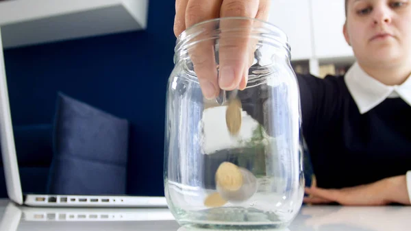 Portrait de jeune femme d'affaires au bureau remplissant pot en verre avec des pièces en métal — Photo