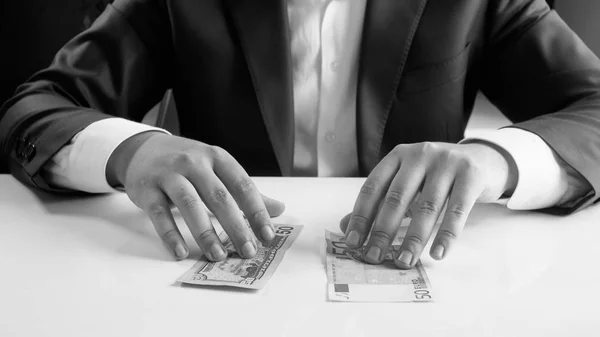 Schwarz-Weiß-Bild eines jungen Geschäftsanlegers, der zwischen verschiedenen Währungen wählen kann — Stockfoto