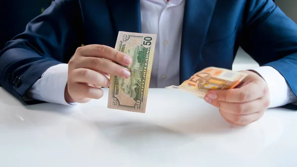 Closeup photo of businessman choosing between using Euro or US dollars currency — Stock Photo, Image