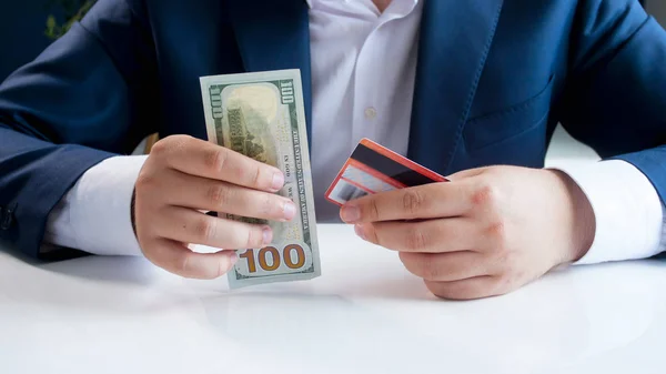 Closeup image of businessman choosing between using credit card or paper money — Stock Photo, Image