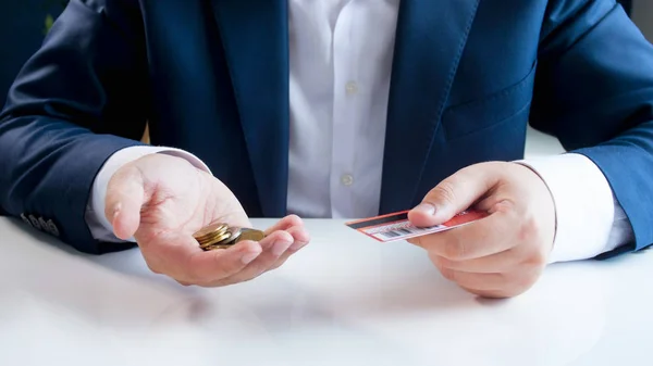 Zbliżenie obrazu biznesmen wyboru między przy użyciu karty kredytowej lub metalowych monet — Zdjęcie stockowe
