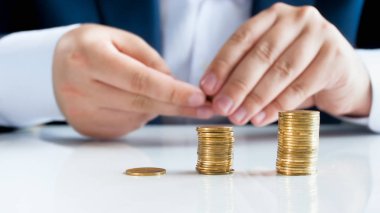 Portre resim erkek işadamı altın sikke yığınlarda beyaz ofis masası üzerinde koyarak.