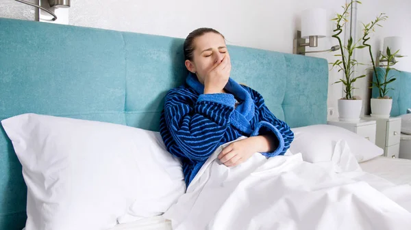 Mujer joven tiene gripe acostada en la cama y tos —  Fotos de Stock