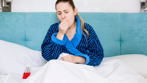 Retrato de una mujer enferma con fiebre acostada en la cama y tos —  Fotos de Stock