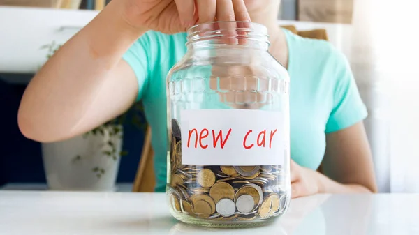 女人把硬币贴在玻璃罐子上的特写图像被标记为购买新车 — 图库照片