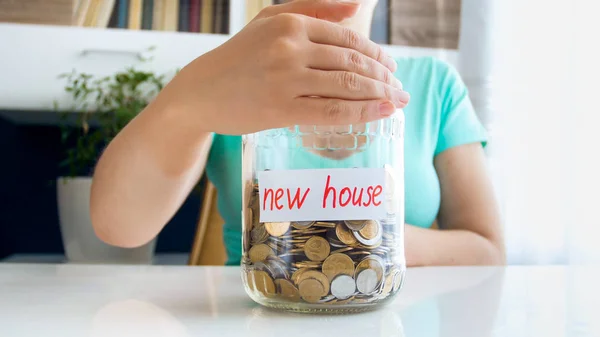 Nahaufnahme Foto einer Frau, die ein Glas mit Ersparnissen für ein neues Haus hält — Stockfoto