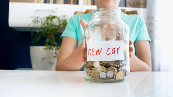 Nahaufnahme Foto einer jungen Frau mit einem Glas voller Ersparnisse für den Kauf eines neuen Autos — Stockfoto