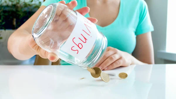 Foto close-up de jovem mulher agitando frasco de vidro com economia de dinheiro — Fotografia de Stock