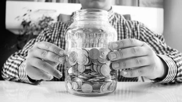 Image en noir et blanc d'un jeune homme avec un bocal plein de pièces de monnaie — Photo