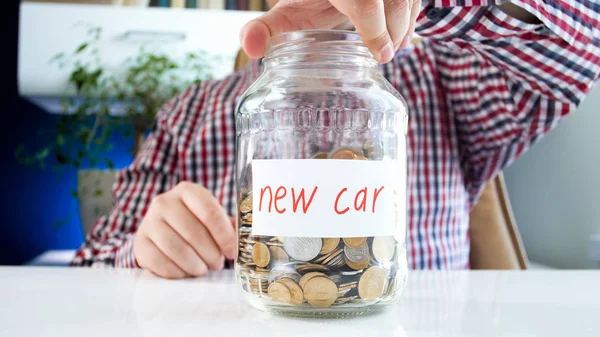 Imagem close-up do jovem segurando frasco de vidro com economia de dinheiro para a compra de carro novo — Fotografia de Stock
