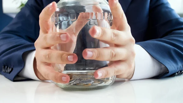 Citra tertutup pengusaha memegang botol kaca dengan beberapa koin di bagian bawah — Stok Foto