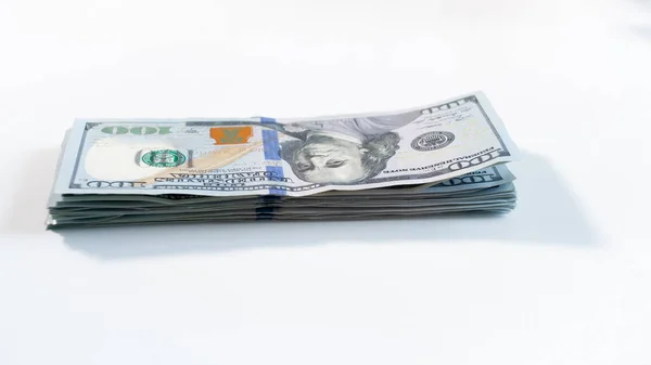 Closeup image of big stack of 100 US dollars lying on white wooden desk — Stock Photo, Image