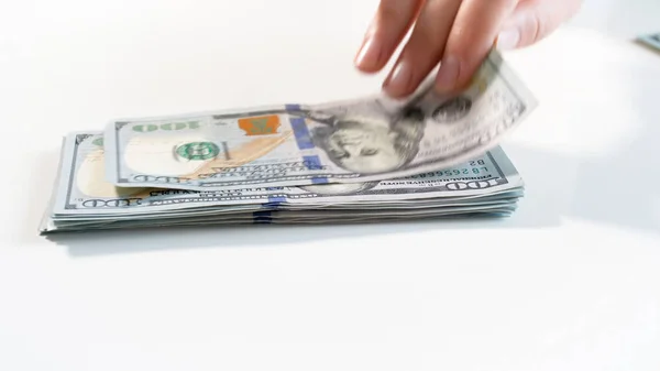 Closeup photo of hand grabbing 100 dollars from big stack of money on white backgorund — Stock Photo, Image