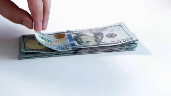 Closeup image of hand taking money from big stack of US dollars on white background — Stock Photo, Image