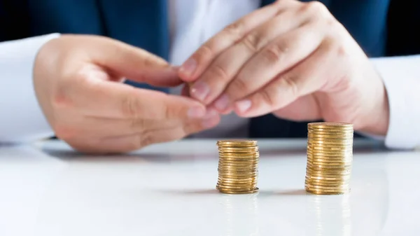 Closeup image of businessman putting golden in high stacks on office desk — Stock Photo, Image