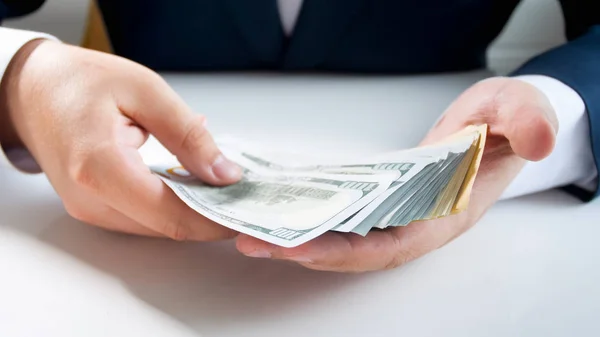 Closeup photo of businessman in suit holding big stack of money — Stock Photo, Image