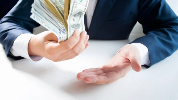 Closeup image of young businessman flapping with big stack of money on hand — Stock Photo, Image