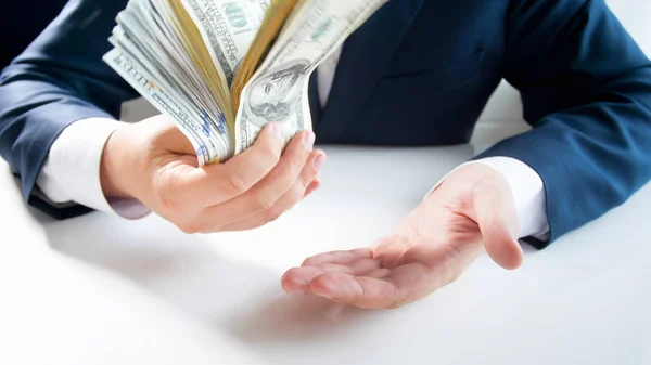 Closeup image of businessman holding big stack of money and flapping the them on hand — Stock Photo, Image