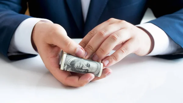 Immagine da primo piano di un giovane in giacca e cravatta che tiene in mano una grande pila di dollari USA — Foto Stock