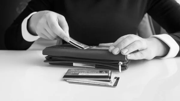 Black and white closeup image of businesswoman putting credit cards in wallet — Stock Photo, Image