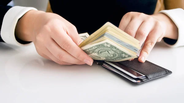 Closeup photo of young rich woman trying to put big stack of money in tight wallet — Stock Photo, Image