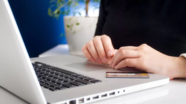 Closeup image of young woman sitting with credit card behind laptop — Stock Photo, Image
