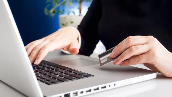 Closeup image of young woman browsing internet and holding credit card in hand — Stock Photo, Image