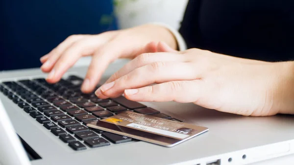 Closeup image of credit card lying on laptop keyboard while woman making online purchases — Stock Photo, Image