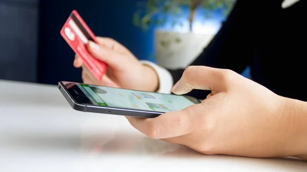 Closeup image of young woman paying with credit card for order in online shop she made on smartphone — Stock Photo, Image