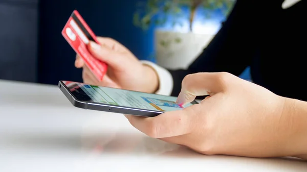 Closeup image of young woman browsing online shop on smartphone and holding credit card — Stock Photo, Image