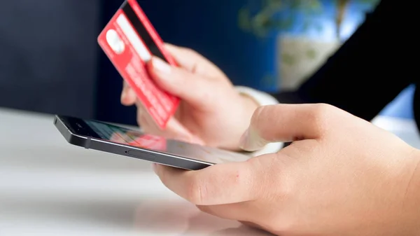 Closeup image of young woman using smartphone holding credit card — Stock Photo, Image