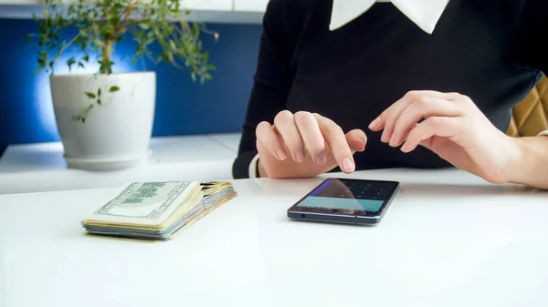 Closeup image of businesswoman using smartphone calculator while counting money — Stock Photo, Image