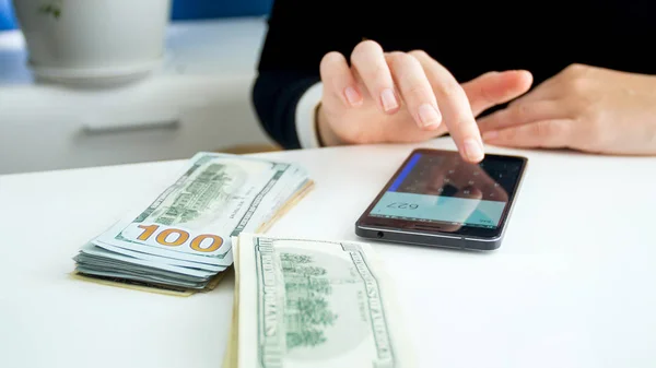 Imagen de primer plano de la mujer de negocios con mucho dinero utilizando la calculadora en el teléfono inteligente —  Fotos de Stock
