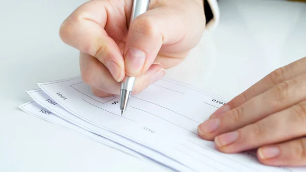 Close-up beeld van vrouwelijke hand ondertekening bank cheque — Stockfoto