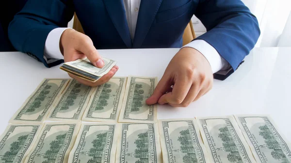 Closeup photo of wealthy businessman laying US dollars banknotes on office desk in long rows — Stock Photo, Image