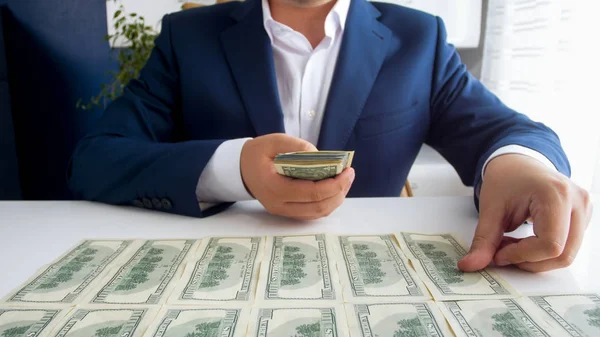 Foto de primer plano del exitoso hombre de negocios que pone dinero frente a él en el escritorio de la oficina —  Fotos de Stock