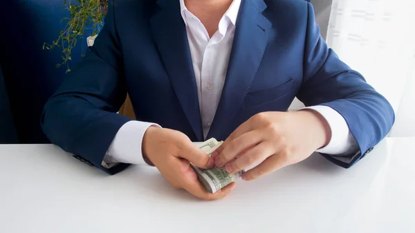 Imagen de primer plano del hombre de negocios en traje que sostiene una gran pila de dinero —  Fotos de Stock