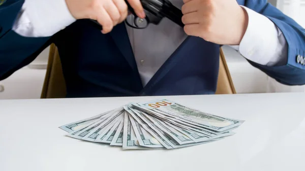 Closeup image of businessman with big stack of money putting handgun in his jacket pocket — Stock Photo, Image